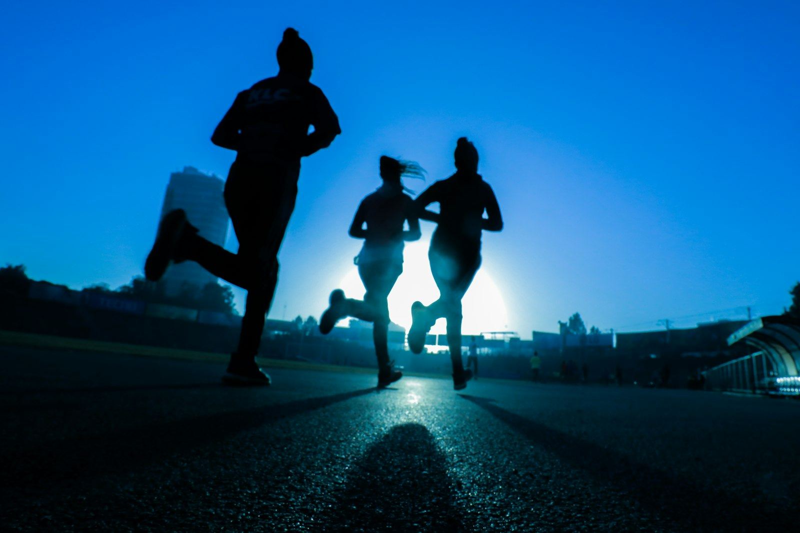 Three club runners pushing together at dusk